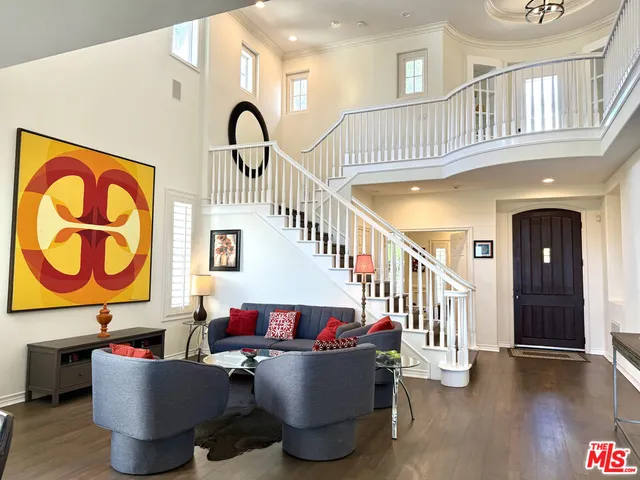 a living room with couches and entryway with wooden floor