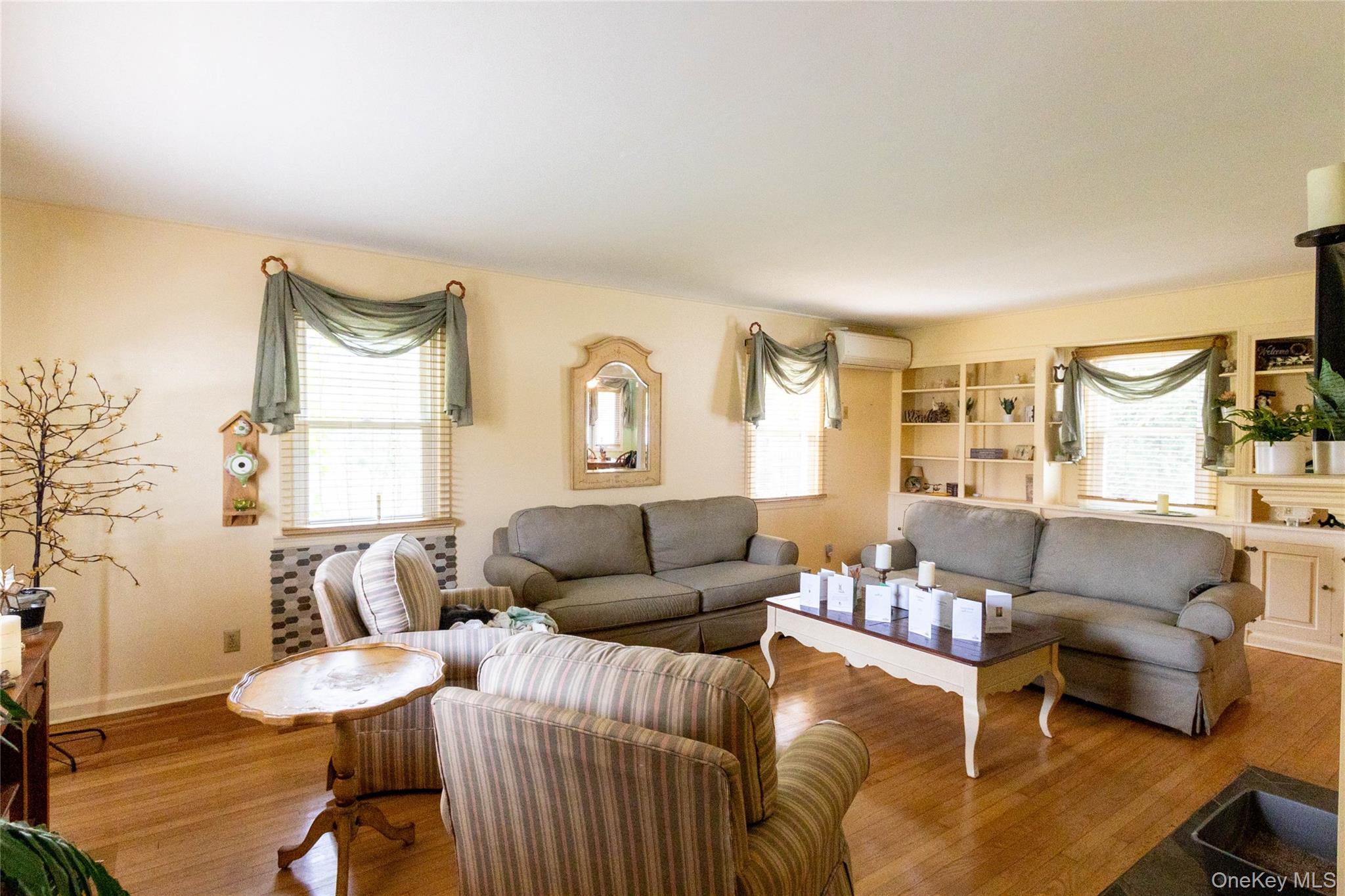 90 Sunset Road Bay Shore, NY 11706 - Photo 13 of 31 Living area with hardwood flooring, multiple windows, built-in shelving, and light-toned walls