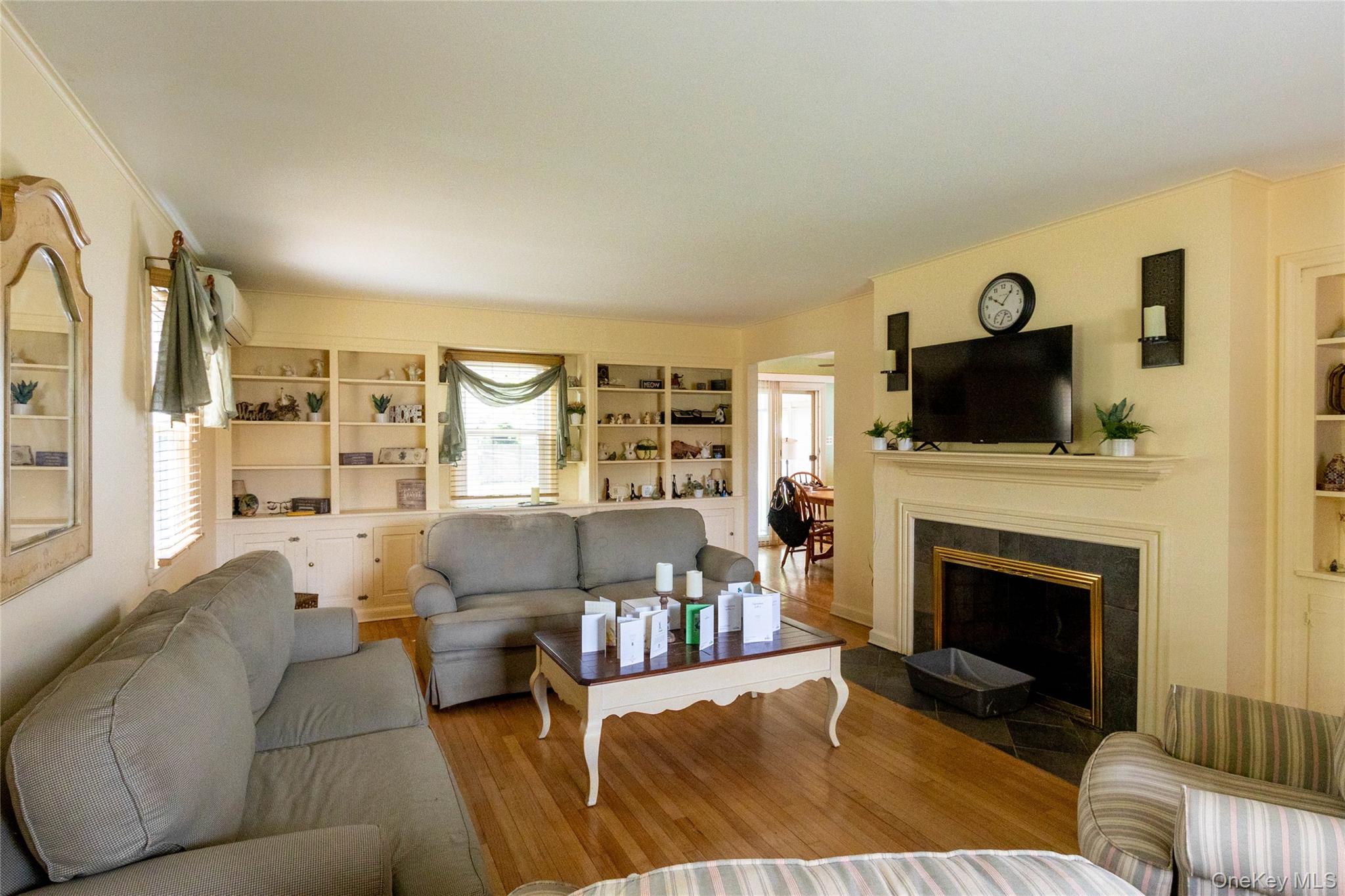 90 Sunset Road Bay Shore, NY 11706 - Photo 14 of 31 Living room featuring hardwood flooring, built-in shelving, a fireplace with a dark stone surround, and crown molding
