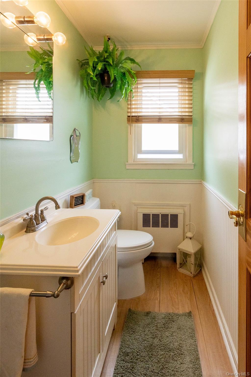 90 Sunset Road Bay Shore, NY 11706 - Photo 22 of 31 Bathroom featuring a vanity with an integrated sink, wood-finish flooring, and wainscoting