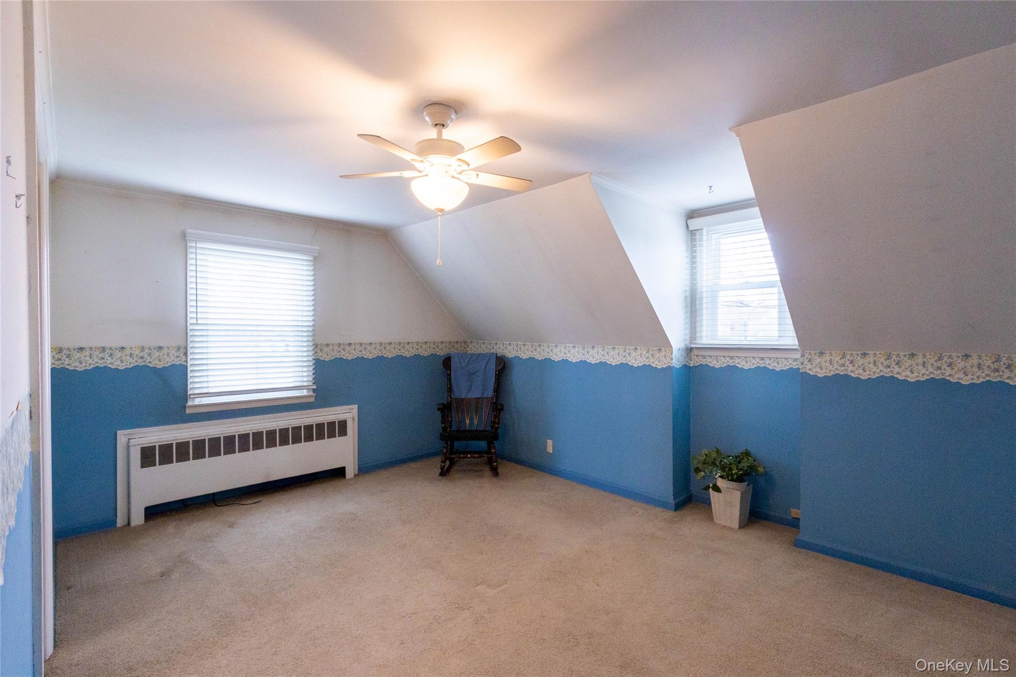 90 Sunset Road Bay Shore, NY 11706 - Photo 27 of 31 Carpeted room featuring a ceiling fan with integrated lighting, two windows with horizontal blinds, an integrated heating unit, and sloped ceiling details