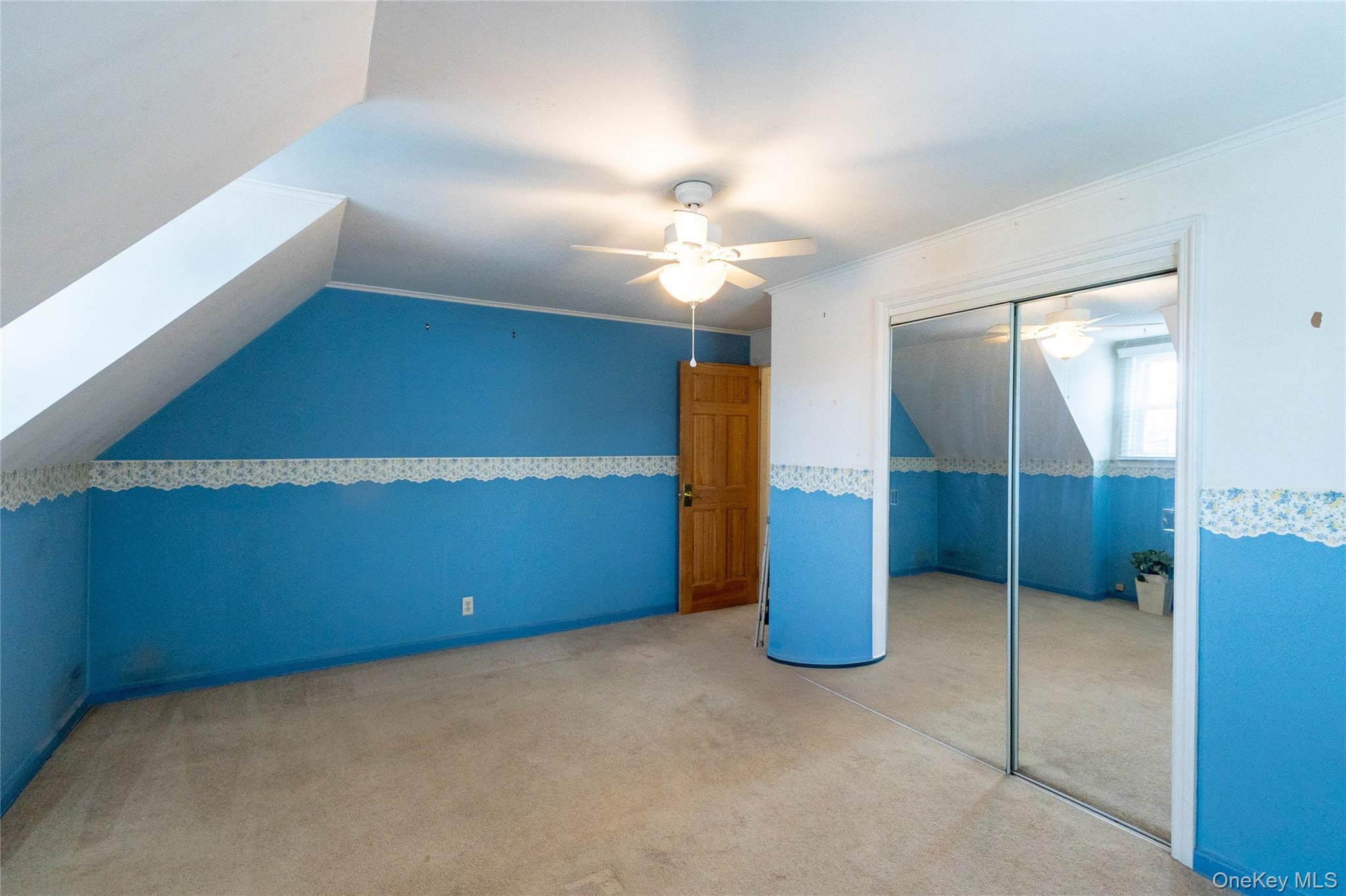 90 Sunset Road Bay Shore, NY 11706 - Photo 28 of 31 Attic room featuring sloped ceilings, a ceiling fan with light fixture, mirrored closet doors, and carpeted flooring