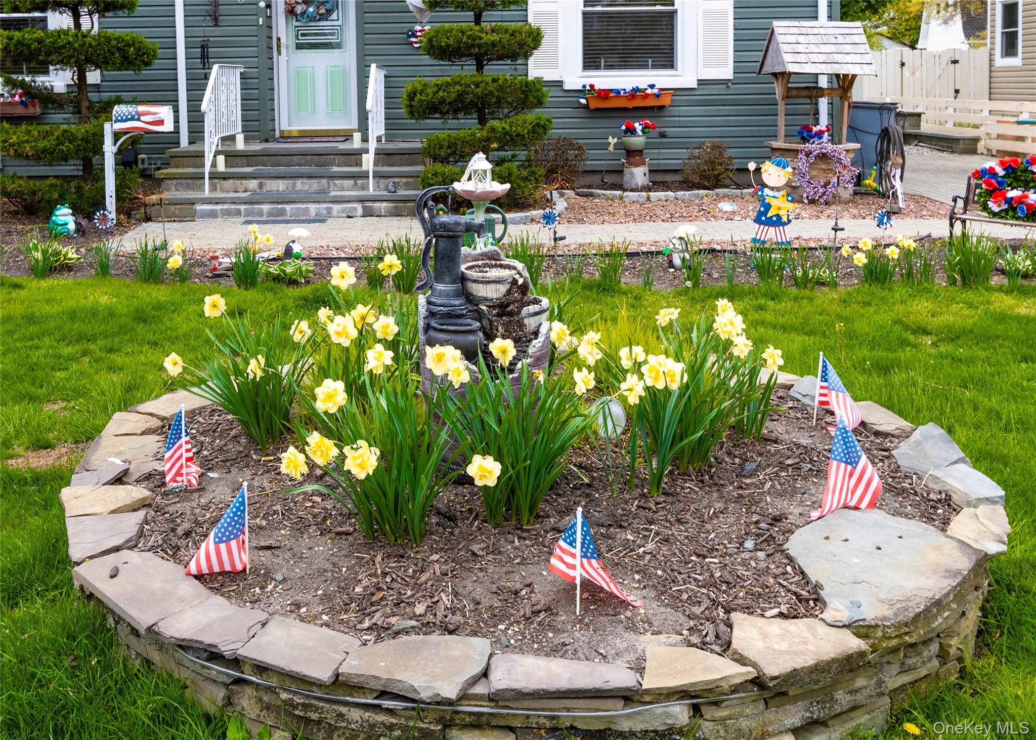90 Sunset Road Bay Shore, NY 11706 - Photo 4 of 31 Front yard featuring a stone-lined flower bed with yellow blooms, a manicured lawn, and a paved walkway leading to the entrance