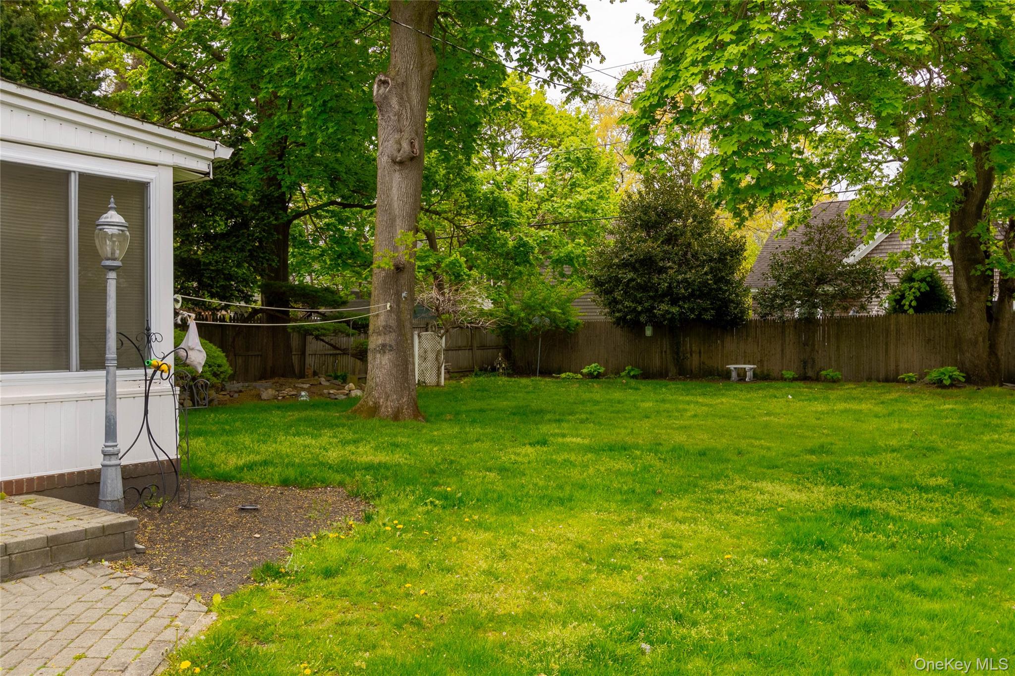 90 Sunset Road Bay Shore, NY 11706 - Photo 5 of 31 Expansive backyard featuring a manicured lawn, mature trees, and a privacy fence