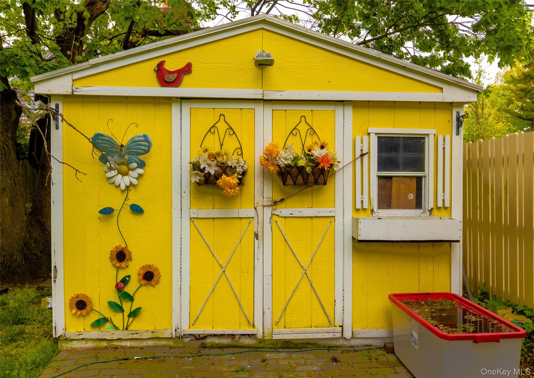 90 Sunset Road Bay Shore, NY 11706 - Photo 6 of 31 Bright yellow exterior shed with white trim, double entry doors, a side window with shutters, and an integrated window box