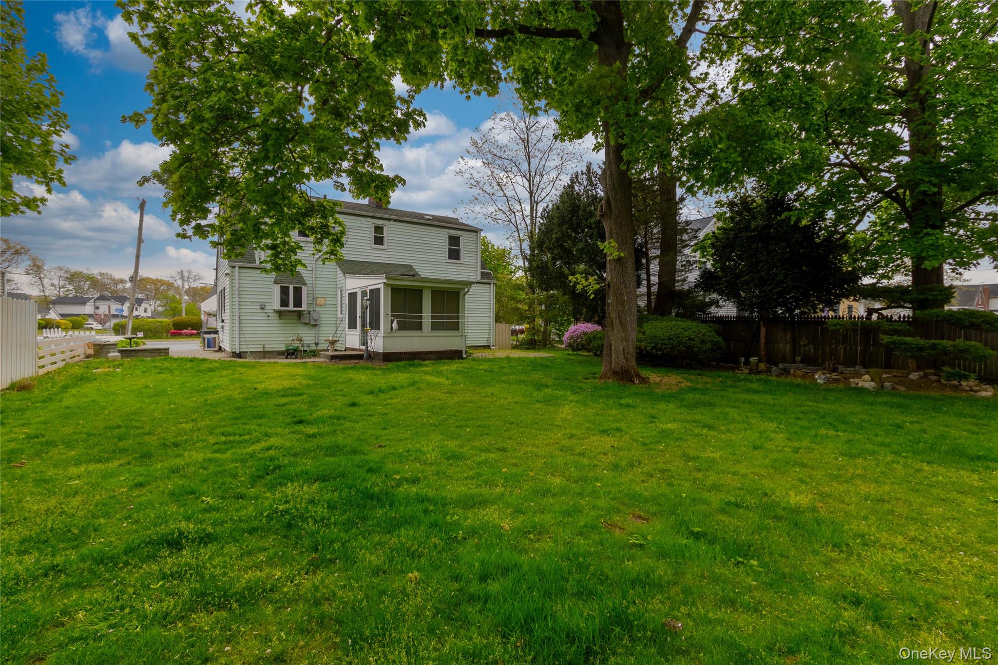 90 Sunset Road Bay Shore, NY 11706 - Photo 7 of 31 Expansive rear lawn featuring mature trees and a screened-in porch with a panel door