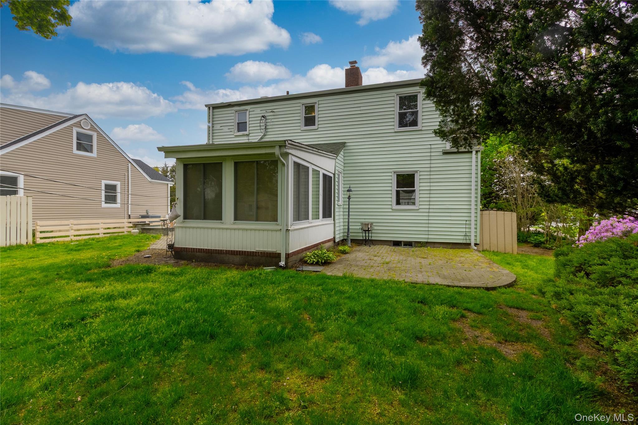 90 Sunset Road Bay Shore, NY 11706 - Photo 9 of 31 Rear exterior featuring light green siding, a screened-in porch with white trim, and a concrete patio