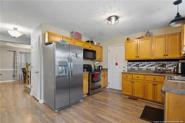 a kitchen with stainless steel appliances granite countertop a refrigerator and a stove top oven