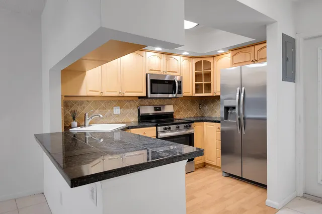 a kitchen with stainless steel appliances granite countertop a refrigerator a stove top oven a sink and dishwasher