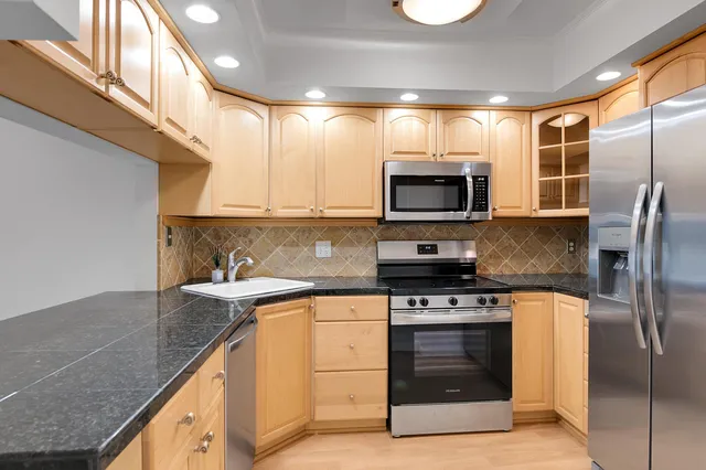 a kitchen with stainless steel appliances granite countertop a stove a sink and a microwave