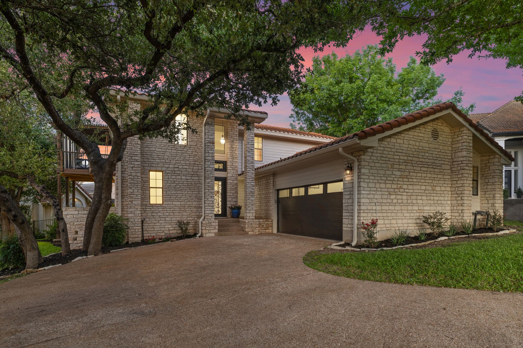 5 Valhalla Court The Hills, TX 78738 - Photo 31 of 34 Tucked beneath a canopy of mature oaks at the end of a quiet cul-de-sac, 5 Valhalla Court makes an unforgettable first impression. The timeless stone façade, tiled roof, and expansive driveway create both elegance and functionality, while lush landscaping enhances the private, serene setting within the gated golf community of The Hills.