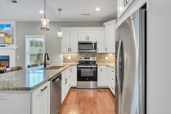 a kitchen with granite countertop white cabinets white stainless steel appliances and a sink