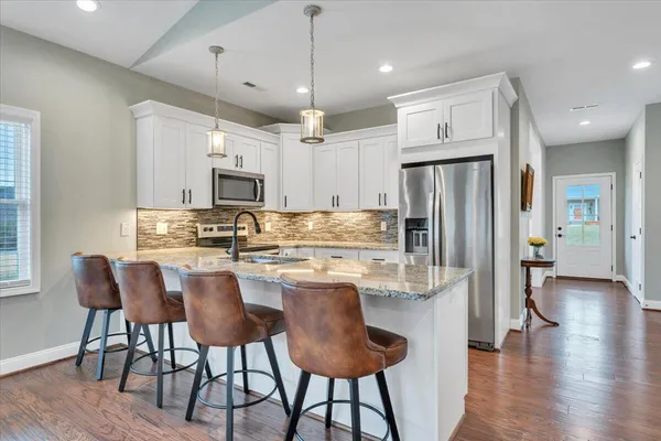 a kitchen with stainless steel appliances kitchen island granite countertop a dining table chairs and white cabinets