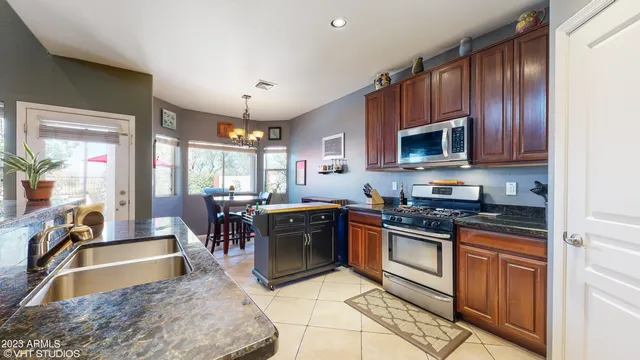 a kitchen with granite countertop a stove top oven a sink a dining table and chairs