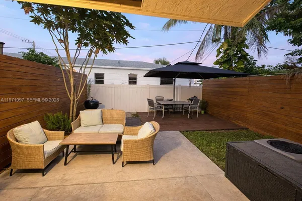 a view of a patio with couches table and chairs under an umbrella with a barbeque
