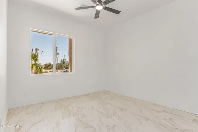 an empty room with a window and a ceiling fan