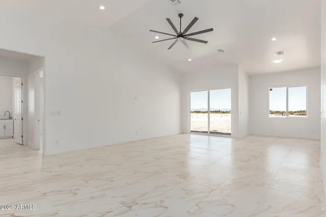 an empty room with windows and ceiling fan