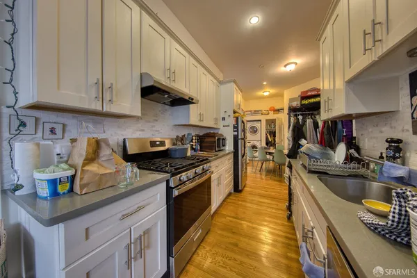 a kitchen with stainless steel appliances granite countertop a sink a stove and a wooden floors