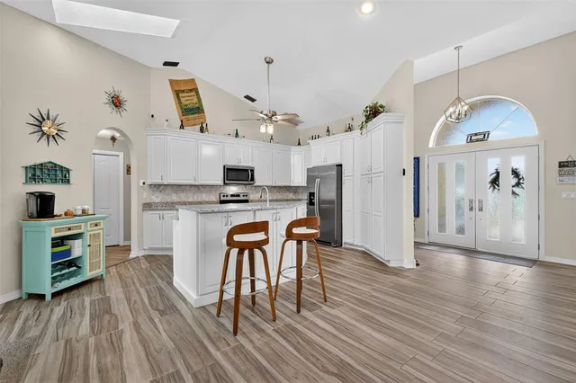 a kitchen with stainless steel appliances a dining table chairs and refrigerator