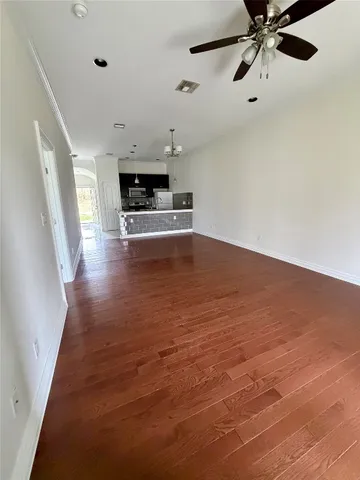 a view of empty room with wooden floor and ceiling fan