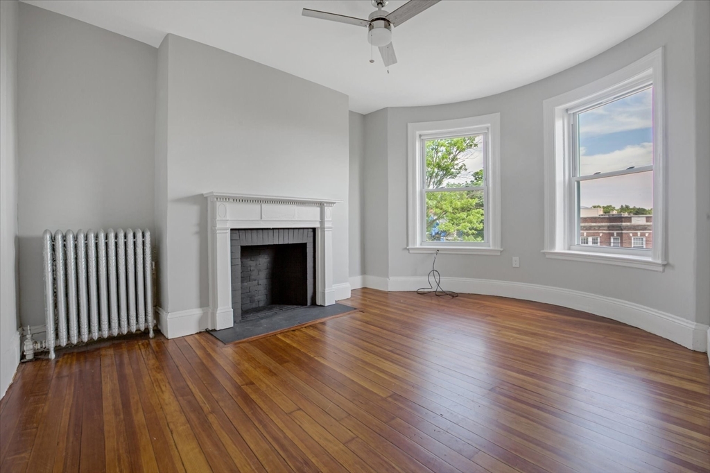 108 Winthrop Road, Unit 1 Brookline, MA 02445 - Photo 12 of 21 an empty room with wooden floor fireplace and windows