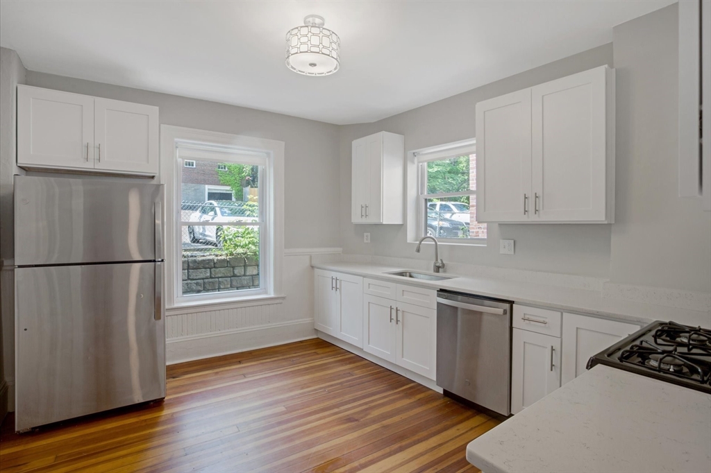 108 Winthrop Road, Unit 1 Brookline, MA 02445 - Photo 2 of 21 a kitchen with wooden floors and white appliances