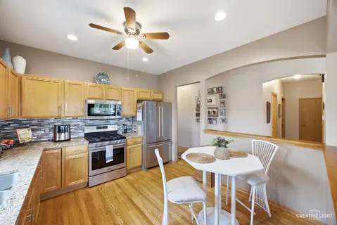 a kitchen with stainless steel appliances granite countertop a stove a sink dishwasher a dining table and chairs with wooden floor