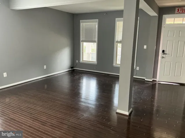 an empty room with wooden floor and windows with curtains