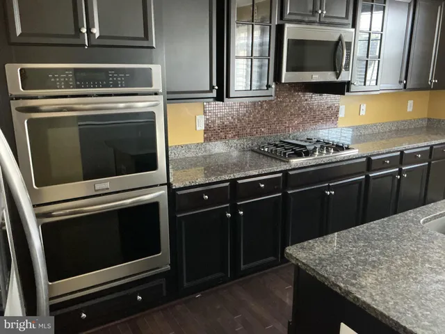 a kitchen with granite countertop cabinets stove and microwave