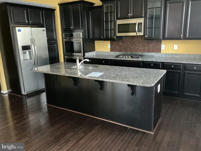 a kitchen with stainless steel appliances granite countertop a sink a microwave counter space and wooden floor