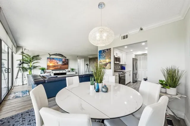 a view of a dining room with furniture a kitchen and chandelier
