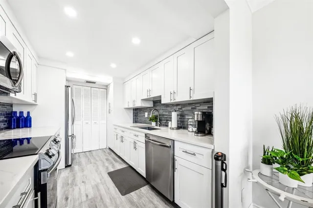a kitchen with stainless steel appliances white cabinets and a hard wood floor