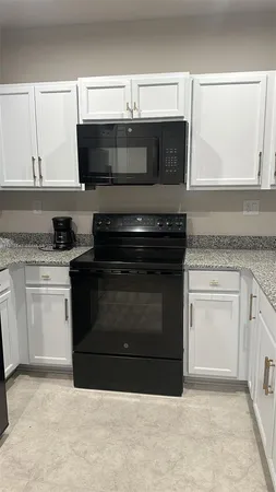 a kitchen with granite countertop a stove and a microwave