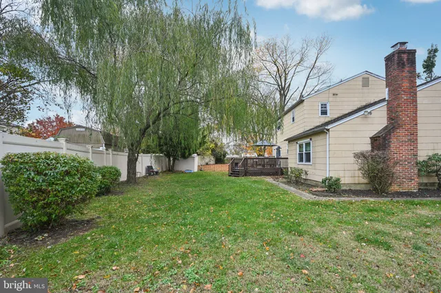 a view of a white house in front of a big yard with large trees