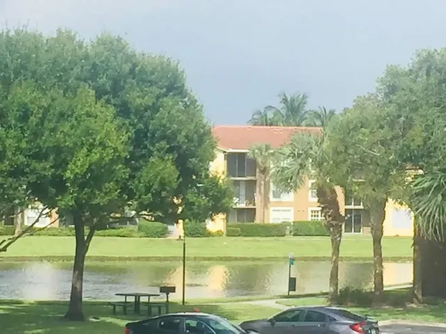a view of a white house with a big yard and potted plants