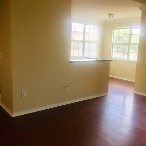 an empty room with wooden floor and windows with curtains