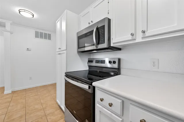 a kitchen with stainless steel appliances granite countertop white cabinets and a stove a oven with white countertops
