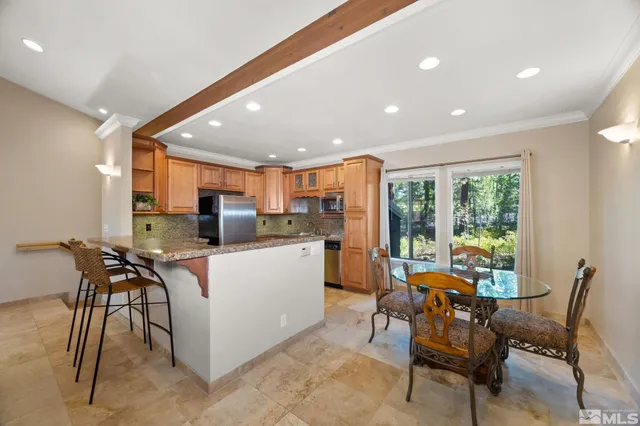 a kitchen with stainless steel appliances kitchen island granite countertop a sink and chairs