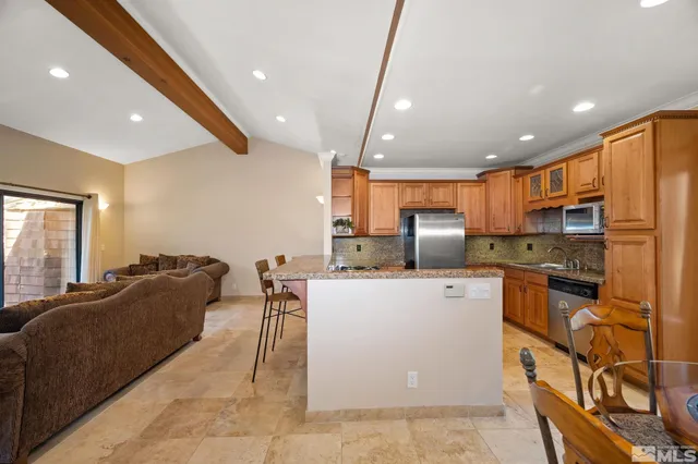 a large kitchen with stainless steel appliances kitchen island granite countertop a refrigerator a stove a sink a dining table and chairs with wooden floor