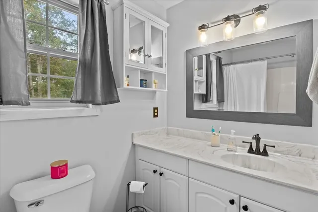 a bathroom with a granite countertop sink vanity mirror next to a window