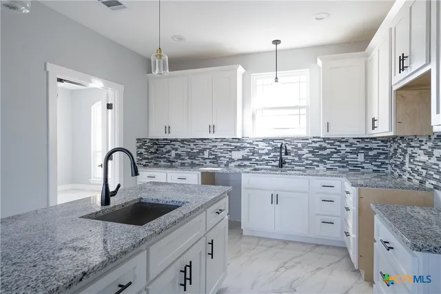 a kitchen with granite countertop a sink stove and cabinets