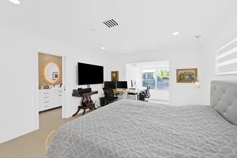 a bedroom with a bed and a flat tv screen on dresser