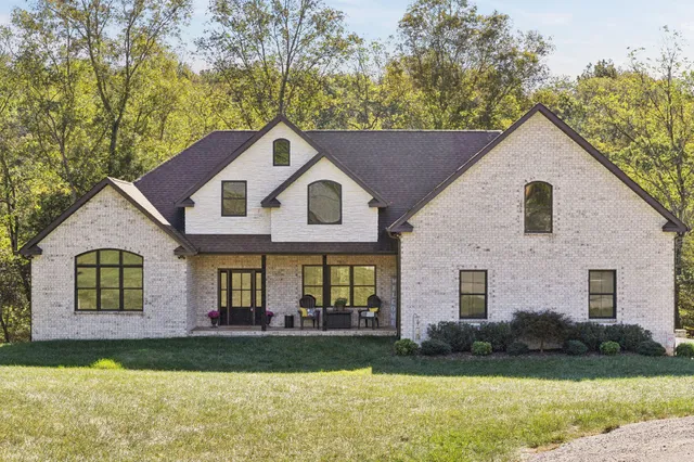 a view of a yard in front of a house with plants and large tree
