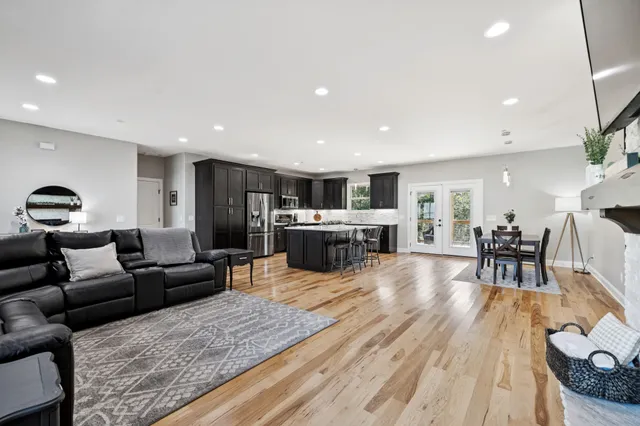 a kitchen with stainless steel appliances granite countertop a stove top oven a sink dishwasher a dining table and chairs with wooden floor