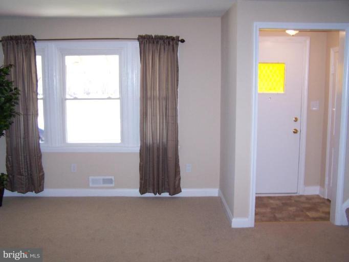 1558 Winford Road Baltimore, MD 21239 - Photo 2 of 9 an empty room with windows and mirror