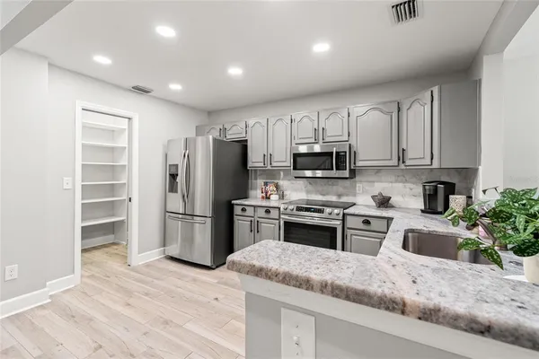 a kitchen with granite countertop a refrigerator stove and oven
