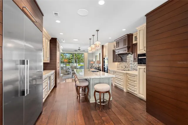 a kitchen with stainless steel appliances kitchen island granite countertop a table chairs and a refrigerator