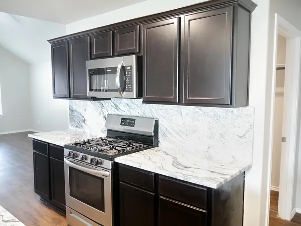 a kitchen with granite countertop stainless steel appliances a stove sink and microwave