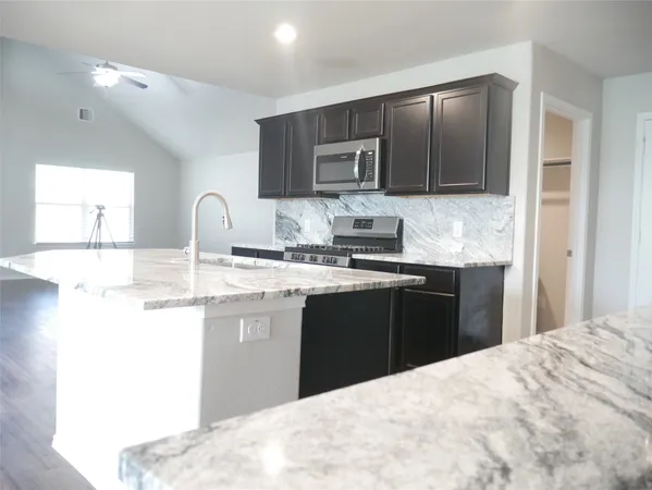 a kitchen with stainless steel appliances kitchen island granite countertop a refrigerator stove top oven and sink