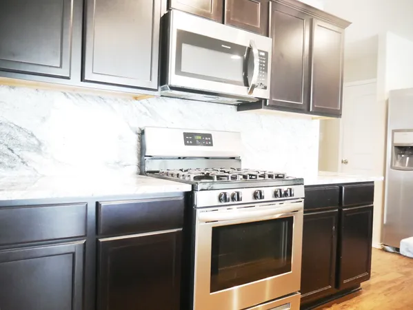 a kitchen with stainless steel appliances granite countertop a stove a microwave and a refrigerator